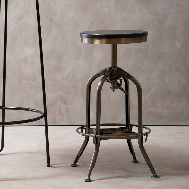 Vintage-style adjustable bar stool against a textured wall.