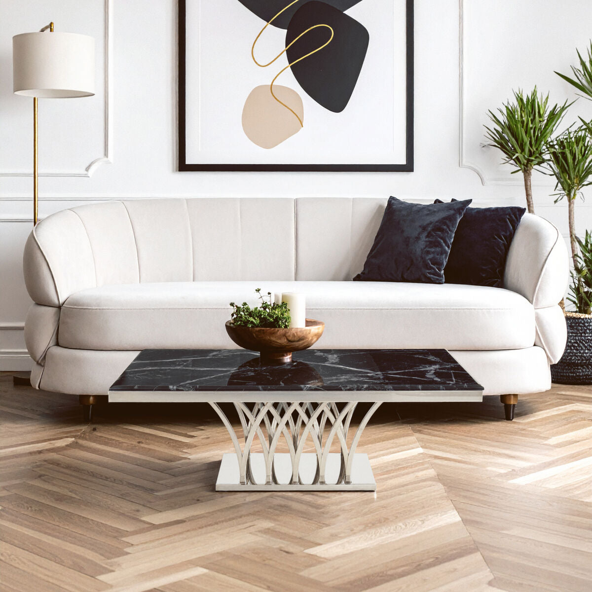 Modern living room with a white sofa, decorative table, and abstract art on the wall.