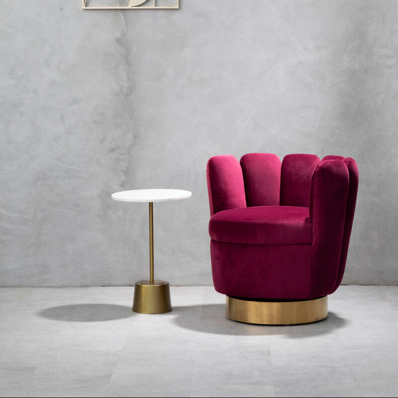 Magenta velvet armchair with gold base next to a small white table against a gray wall.