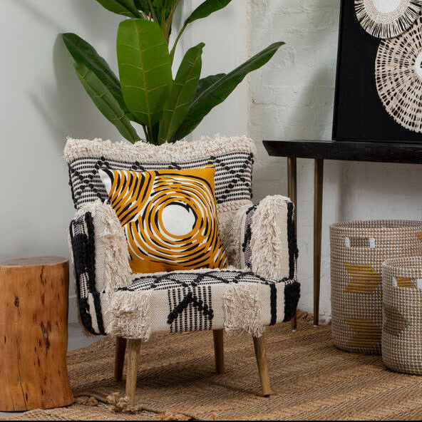 Decorative armchair with a pillow, table with decorative items, and wall art in a room.