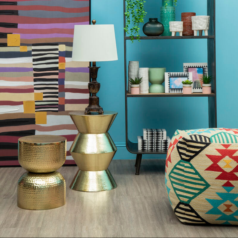 Decorative room interior with a shelf, lamp, and colorful ottoman against a blue wall.