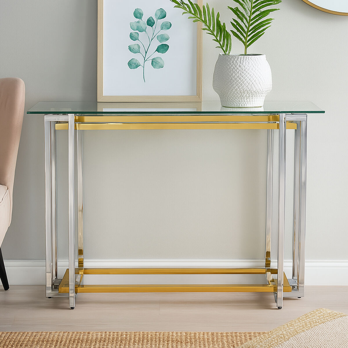 Console table with gold and silver base and glass top in a room setting.