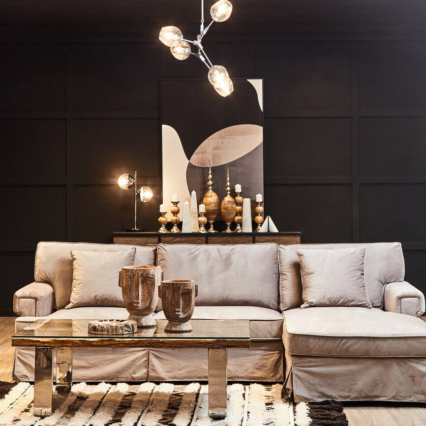 Modern living room with a gray sofa, glass coffee table, and decorative wall art.