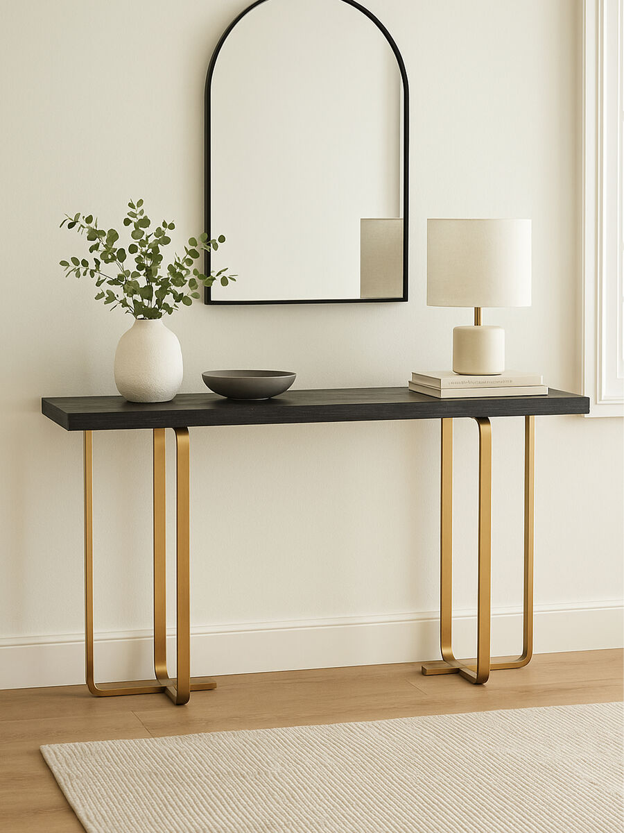Console table with gold legs, black top, and decorative items in a room setting.