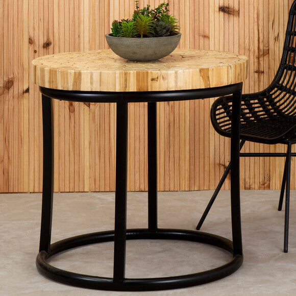 Black wicker chair and round wooden table against a wooden wall.
