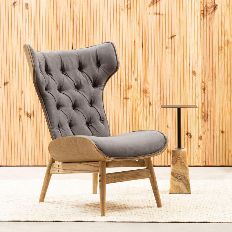 Gray upholstered chair with wooden frame against a wooden paneled wall.
