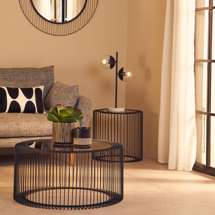 Modern living room with round wire coffee table, mirror, and side table.