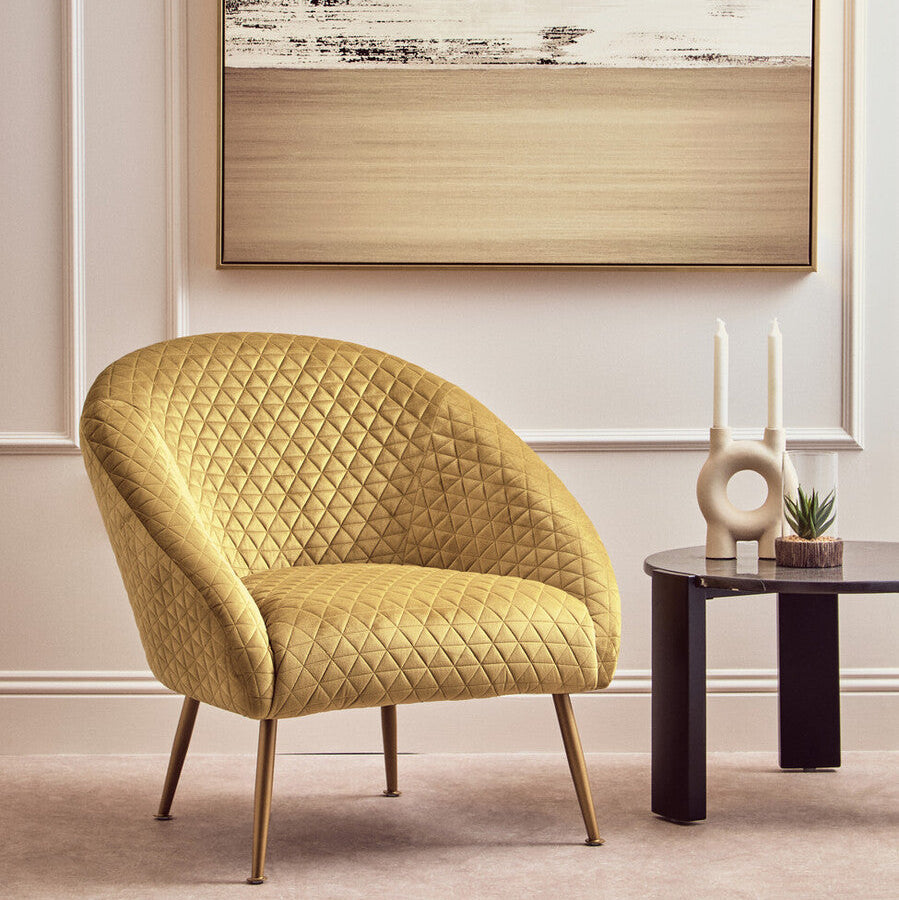 Yellow quilted armchair in a room with a abstract painting on the wall.