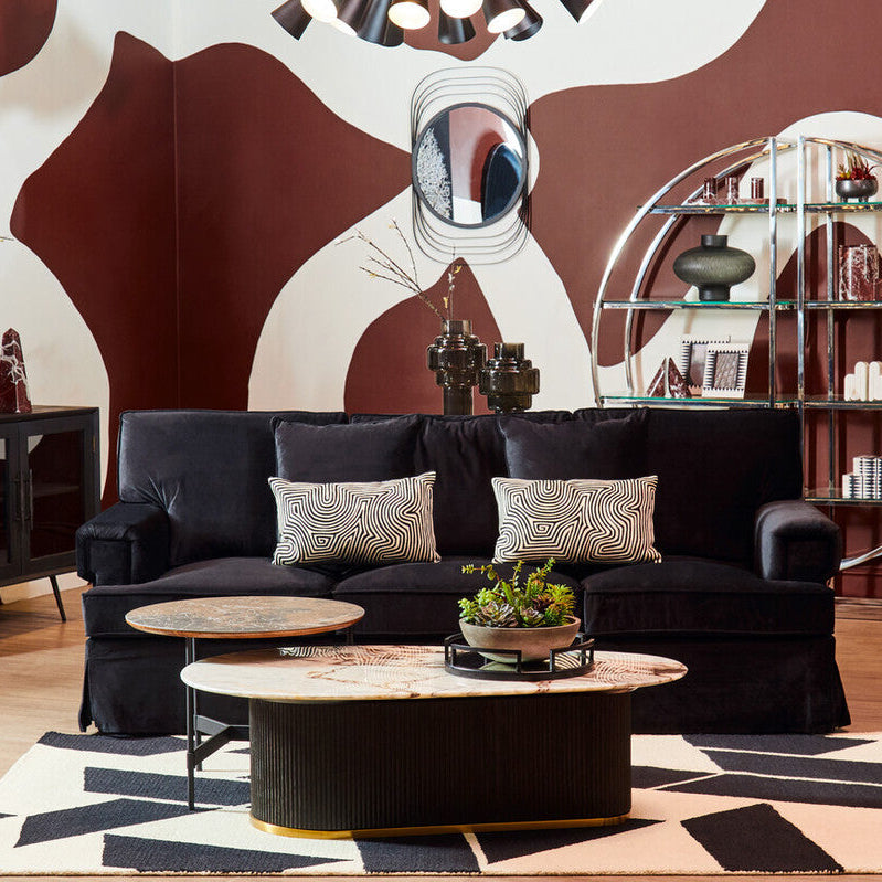 Modern living room with black sofa, round coffee table, and abstract wall design.