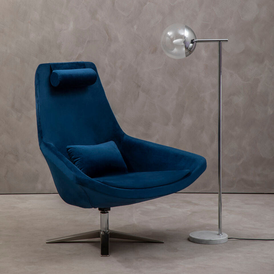 Blue armchair with a floor lamp against a textured wall.