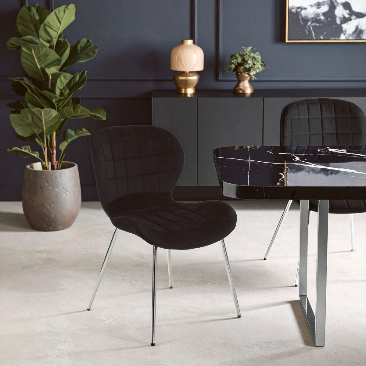 Modern dining room with black chairs, a marble table, and decorative plants.