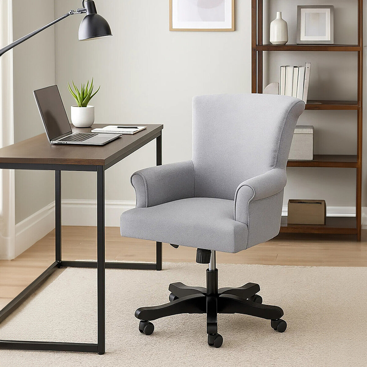Gray office chair in front of a wooden desk with a laptop in a home office setting.