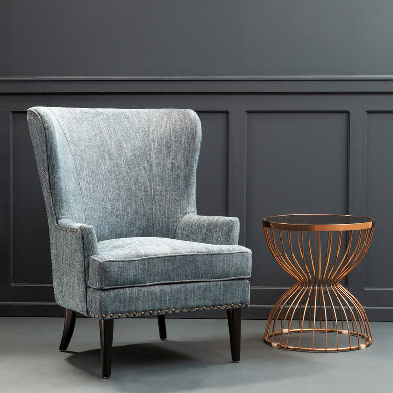 Gray armchair and bronze side table against a dark gray wall