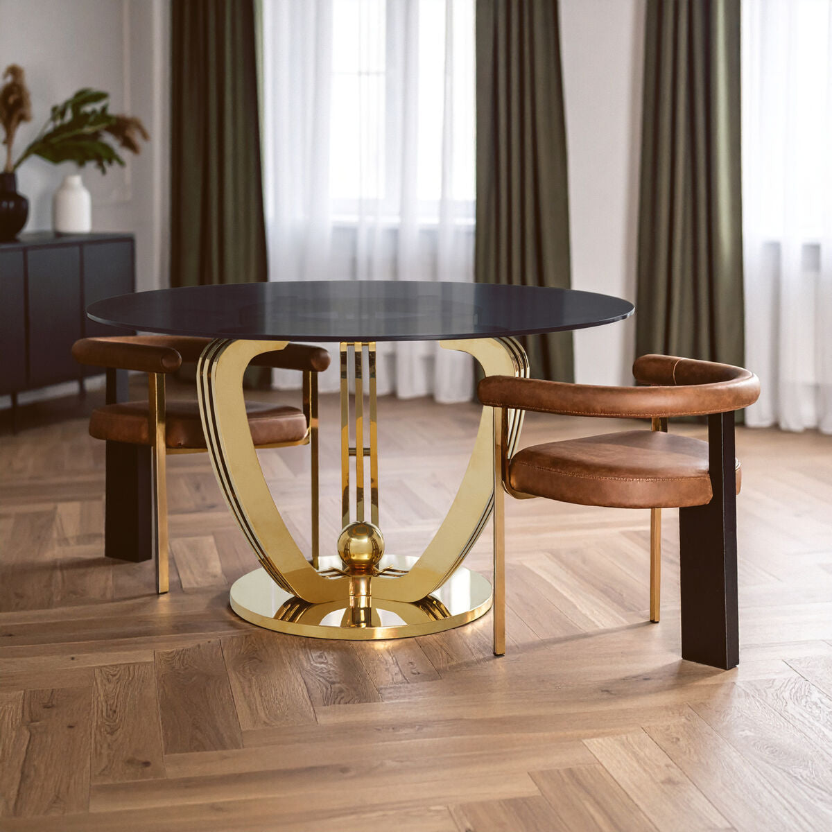 Dining table with gold legs and brown chairs in a room with curtains and a cabinet.