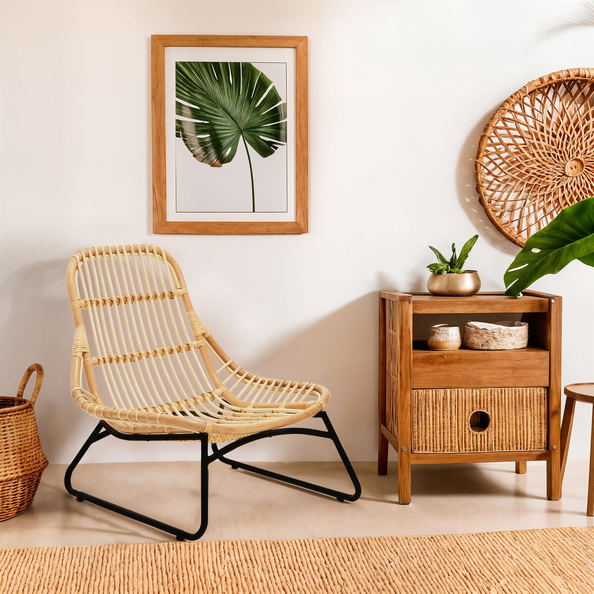Rattan chair and wooden side table in a room with a plant and wall art.
