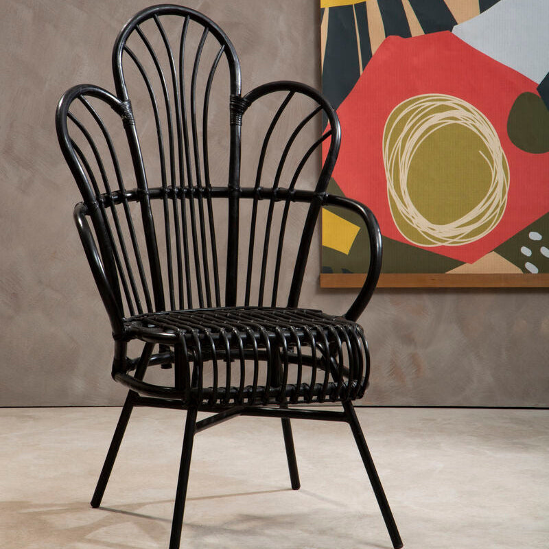 Black wicker chair in a room with a colorful abstract painting on the wall.