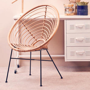 Wicker chair in a room with a white filing cabinet and desk lamp.