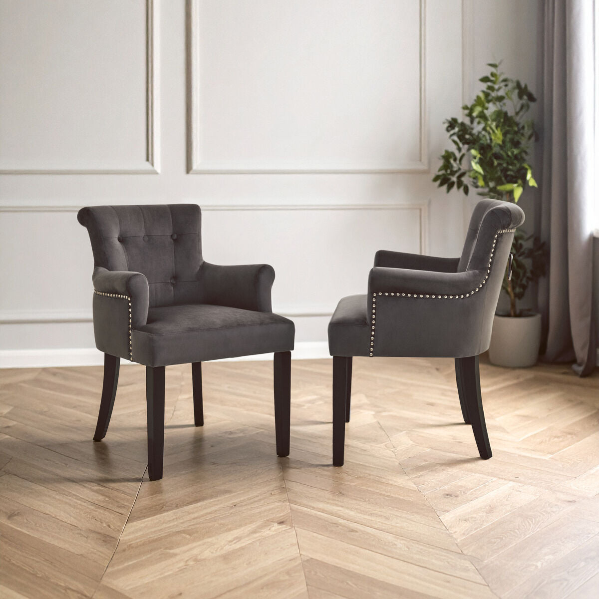 Two gray armchairs in a room with wooden flooring and a plant.