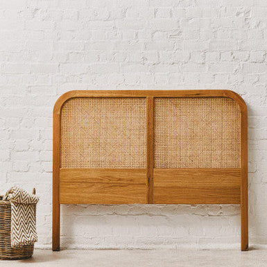 Wooden headboard with wicker panels against a white brick wall.
