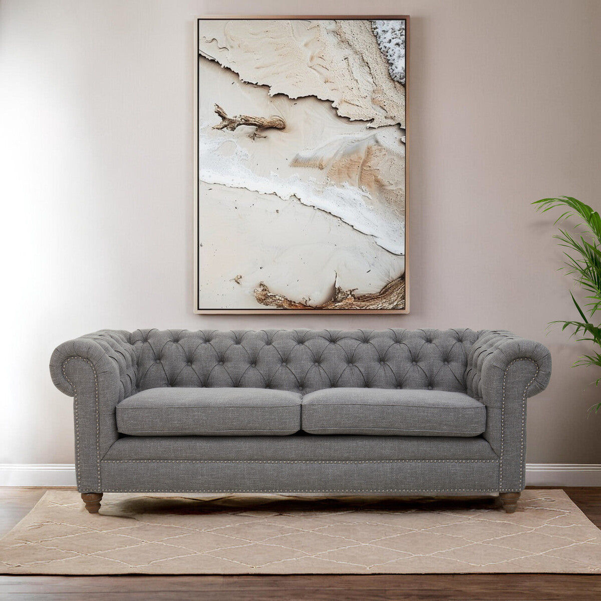 Gray tufted sofa in a living room with a large abstract painting on the wall.