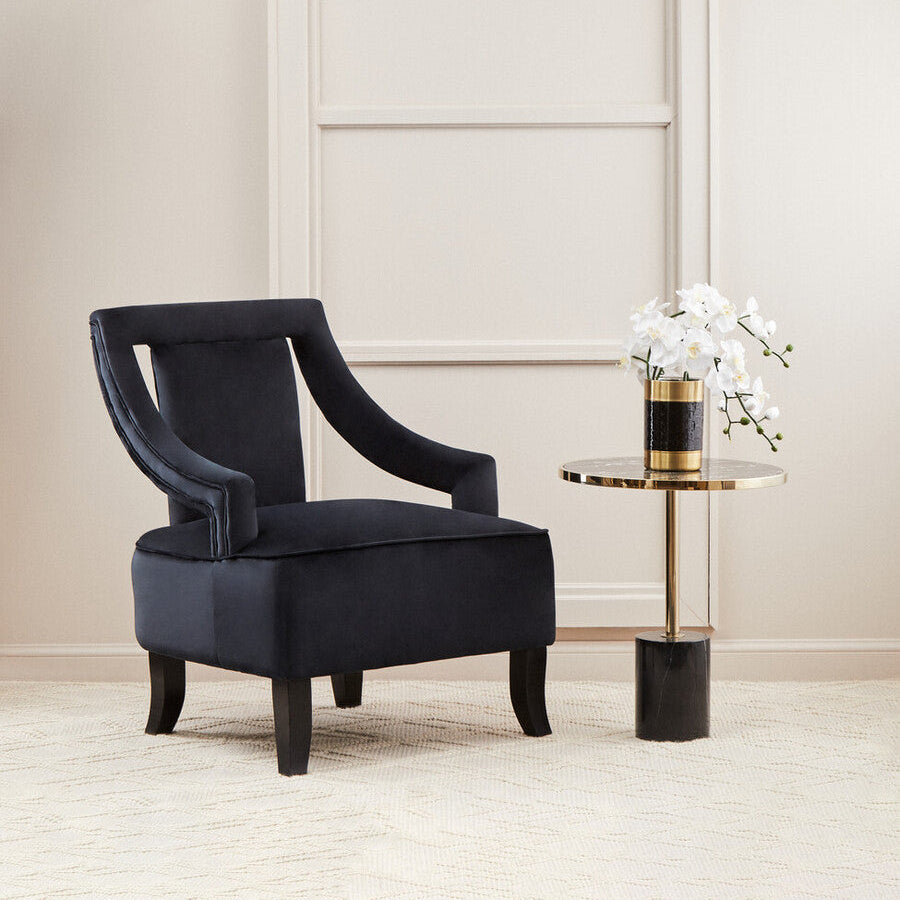 Black armchair in a room with a side table and decorative wall light.