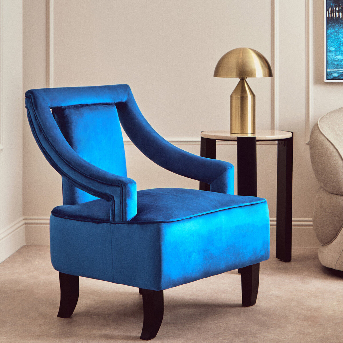 Blue armchair in a room with a gold lamp and beige walls