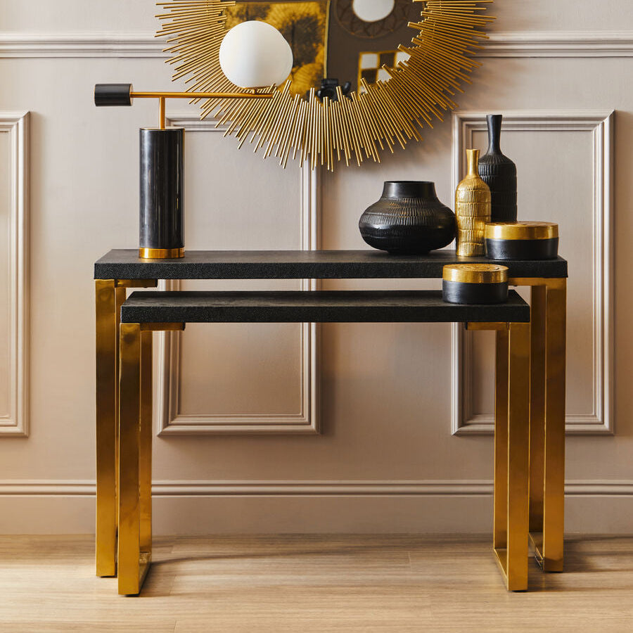 Decorative console table with gold and black accents against a neutral wall.