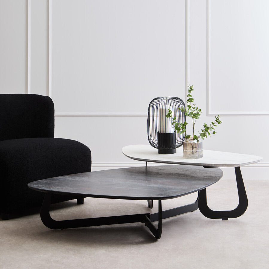 Modern living room with a black armchair, coffee table, and side table against a white paneled wall.
