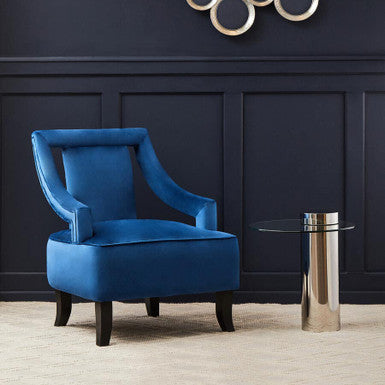 Blue armchair in a room with a decorative wall piece and glass table.