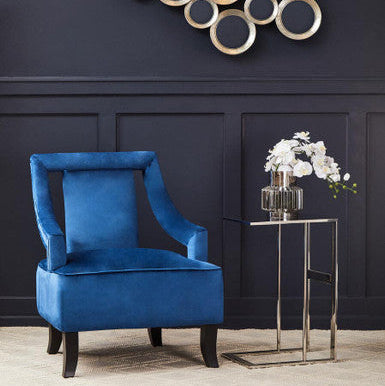 Blue armchair in a room with decorative wall art and a small table with flowers.