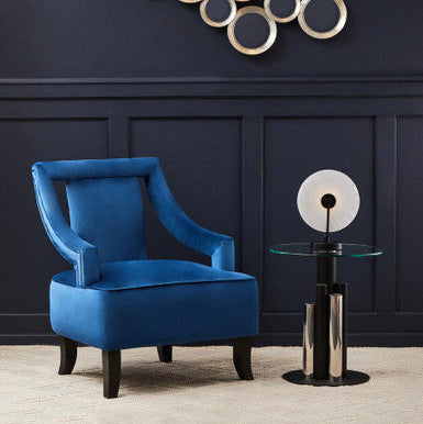 Blue armchair in a room with decorative wall art and a side table.