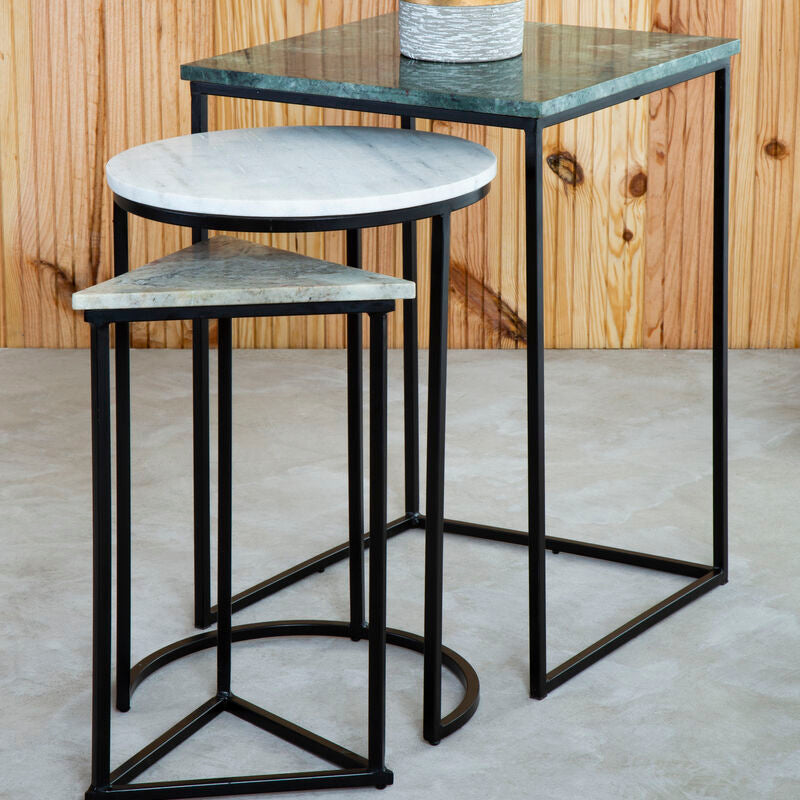 Set of three nesting tables with marble-like tops against a wooden wall.