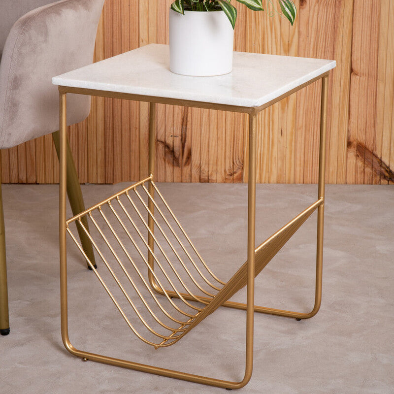Small side table with marble top and gold metal frame next to a chair against a wooden wall.
