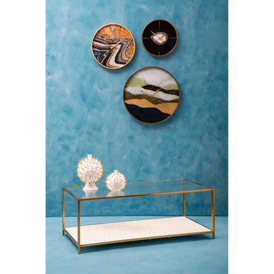 Decorative wall art with circular designs above a glass coffee table on a blue background