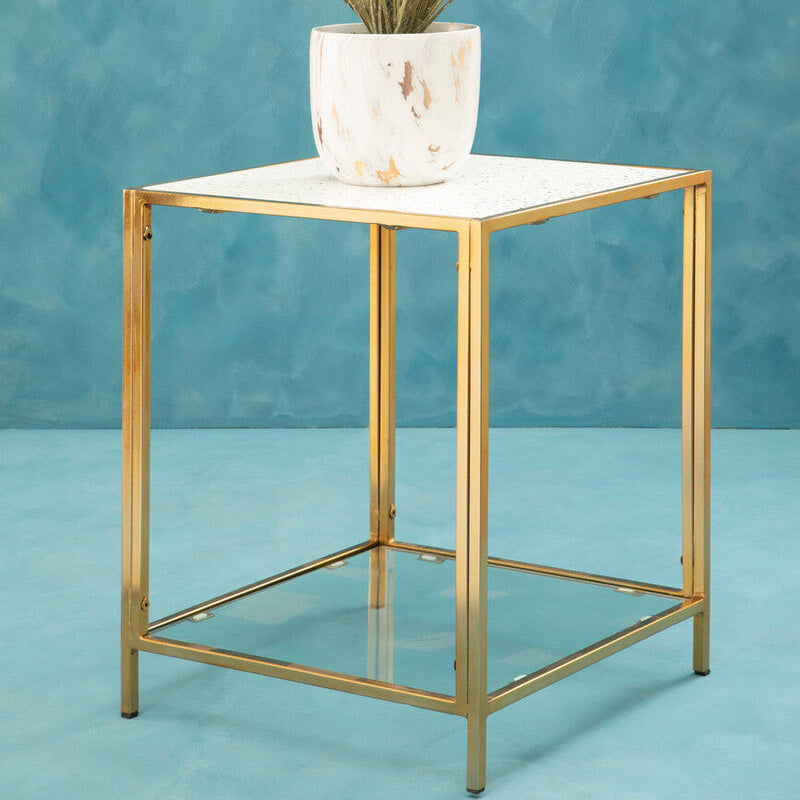 Gold side table with a white marble top and a plant on a blue background