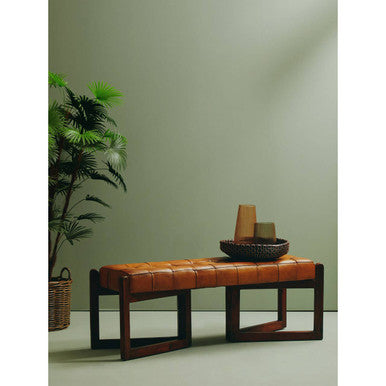 Brown leather bench with a bowl of vases against a green wall