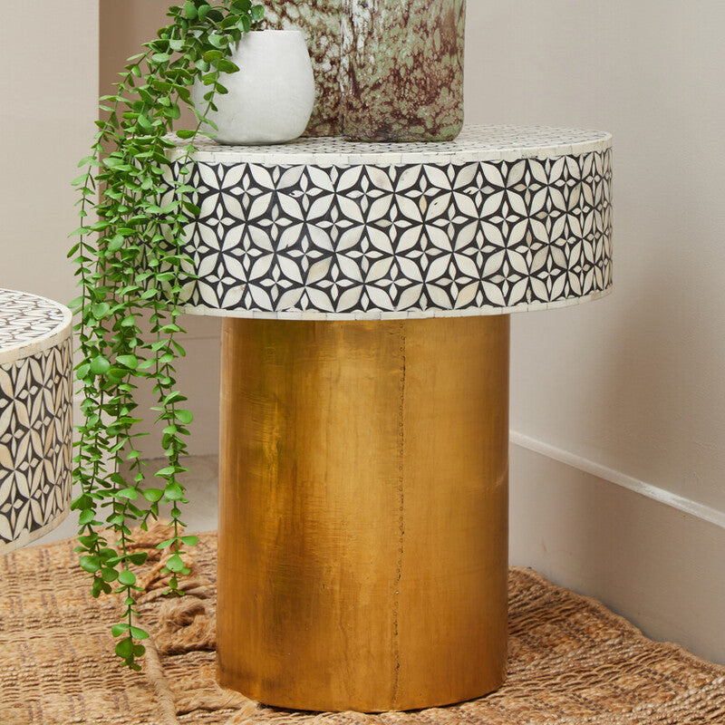 Small round wooden table with a patterned white top, accompanied by decorative vases and a plant.