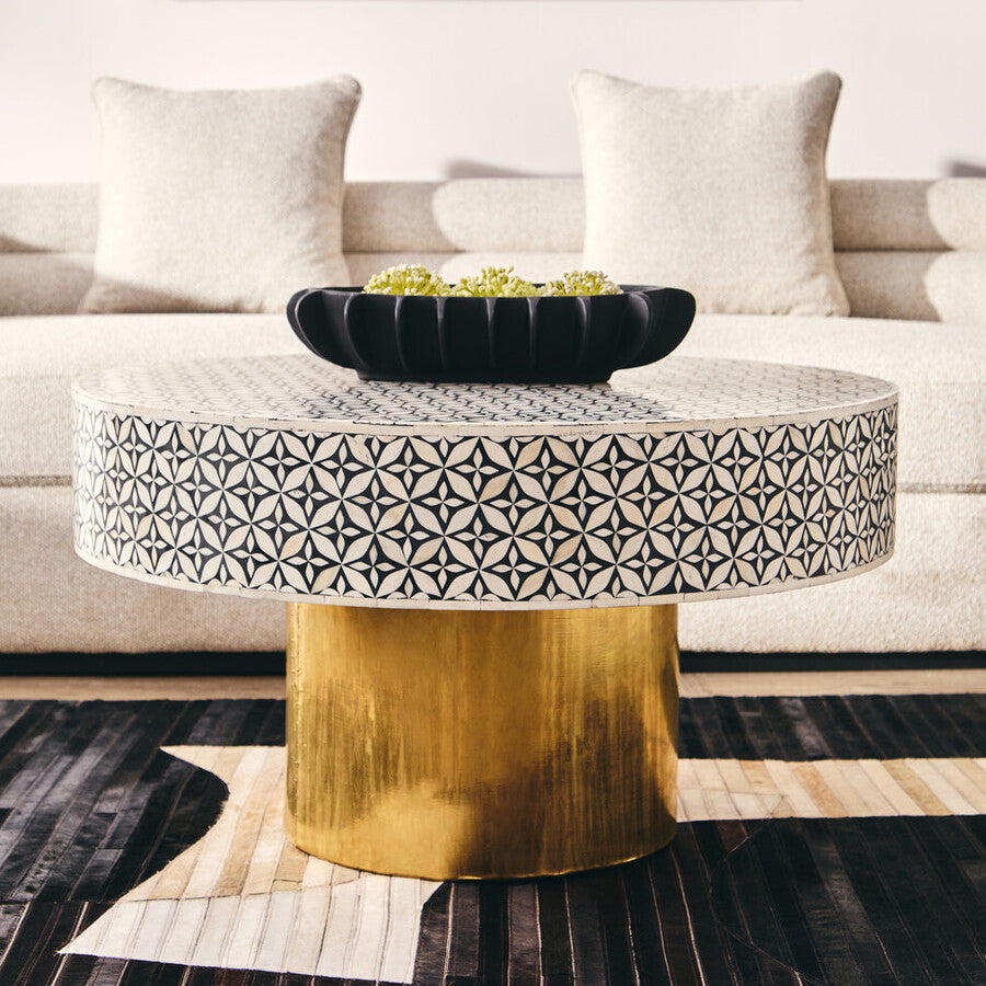 Round coffee table with geometric pattern and gold base in a living room setting