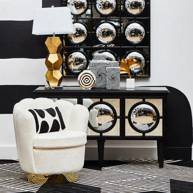 Decorative console table with mirror finish, white chair, and abstract wall art.