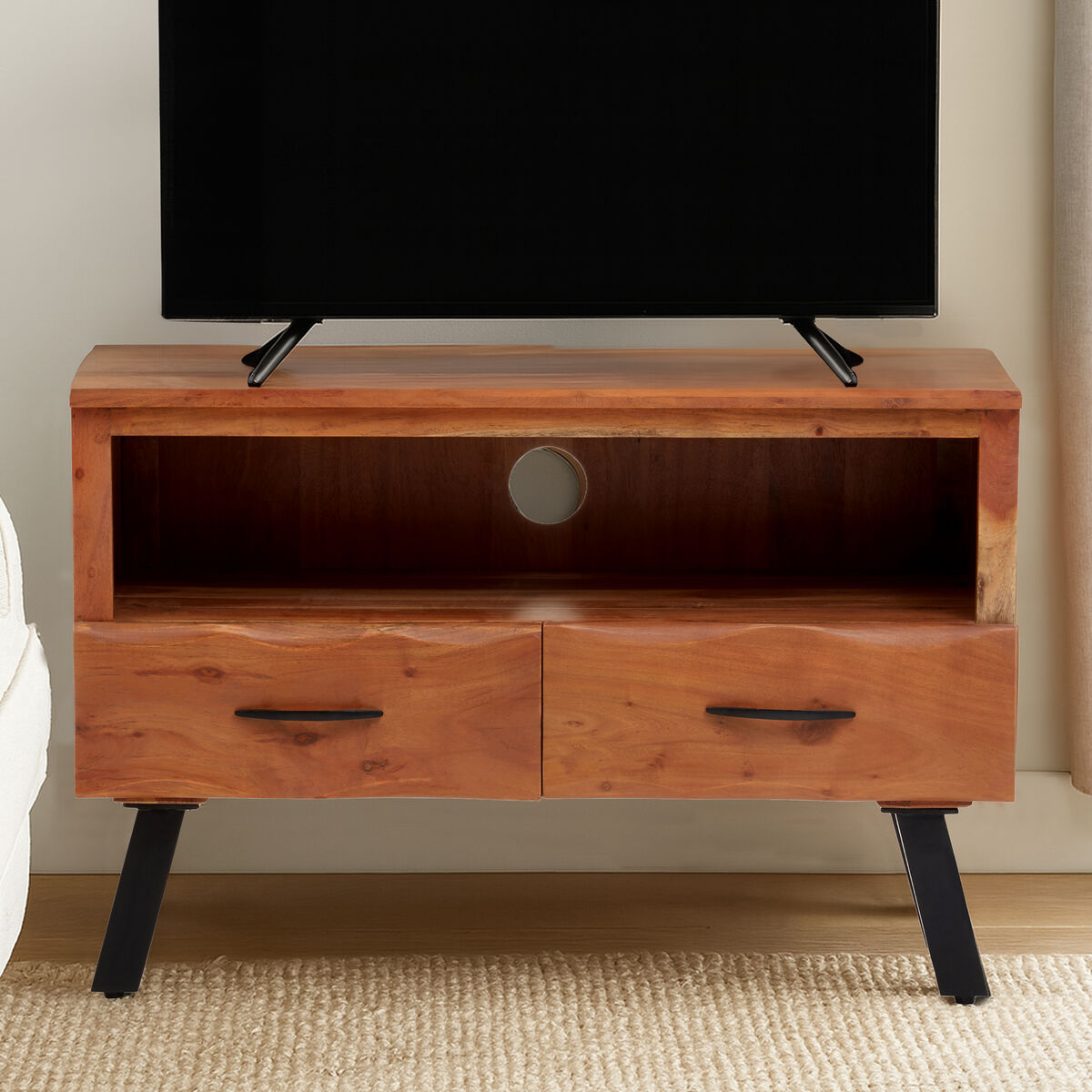 Wooden TV stand with two drawers and a television on top, in a room setting.