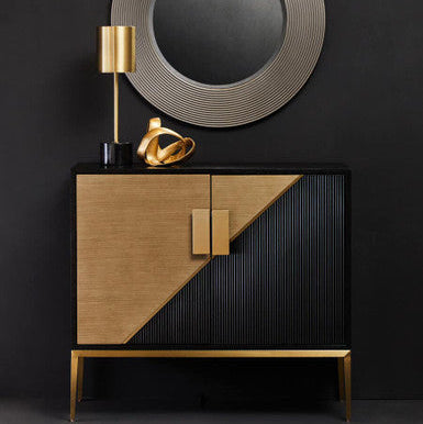 Modern cabinet with geometric design against a dark wall with round mirror and gold lamp.
