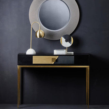 Modern console table with decorative mirror and lamps against a dark wall
