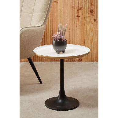 Small round table with a white top and black base in a room with wooden wall and beige chair.