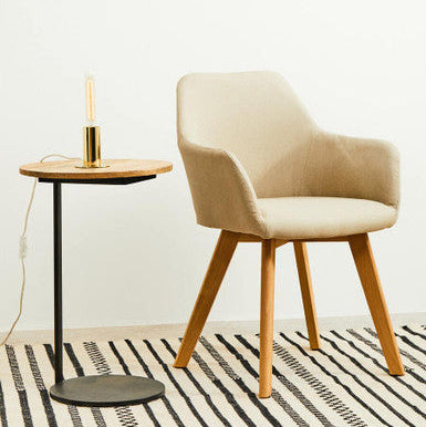 Beige chair and small round table with a candle in a minimalistic room.