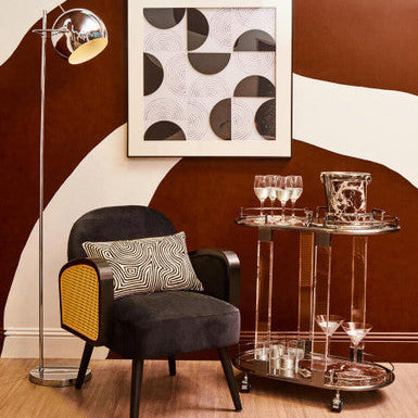 Modern interior with a dark armchair, decorative pillows, a floor lamp, and a wall art piece.