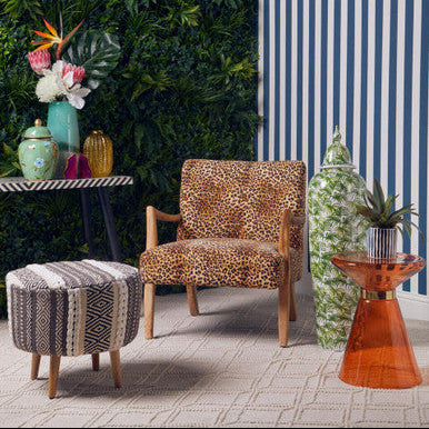 Decorative room with leopard print chair, patterned ottoman, and striped wall.