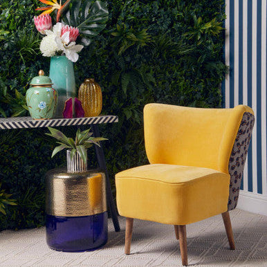 Yellow chair in a room with decorative plants and colorful vases.