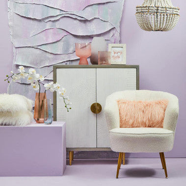 Decorative room with a chair, cabinet, and wall art on a light purple wall.