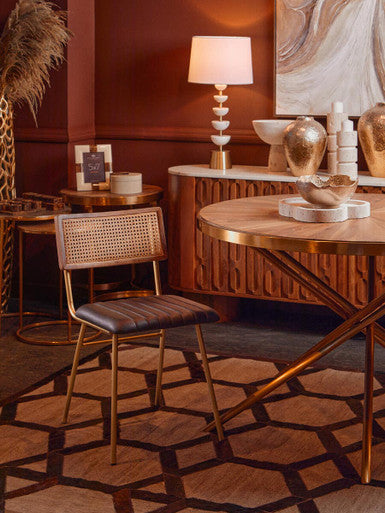Decorative interior setting with a wooden chair, round table, and wall art.