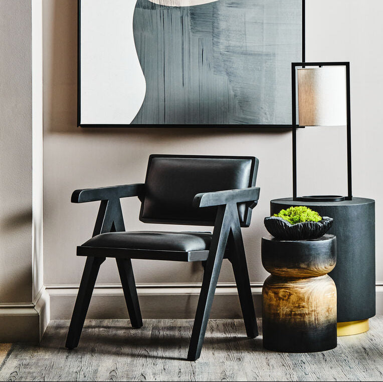 Modern interior with abstract art, black chair, and decorative plants.